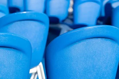 Brightly illuminated close-up of multiple blue plastic chairs Stock Photos