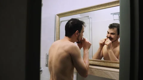 Brightly lit bathroom scene showing man focused on his wardrobe preparation Stock Footage 343957481