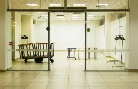 Brightly lit empty shop unit with discarded furniture and strip lights Stock Photos