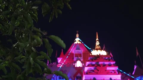 Brightly lit religious temple at night surrounded by lush green trees and i.. Stock Footage 316968706