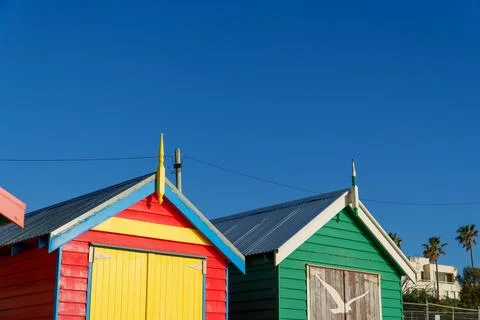 Brightly Painted Bathing Boxes With Unique Doors Stand Against a Cloudless .. Stock Photos