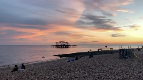 Brighton beach, at sunset, the old pier in the background, people on the beach Stock Footage 141873092
