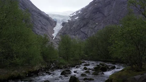 Briksdal glacier with glacial river in the foreground on a rainy day in Norway Stock Footage 235153908