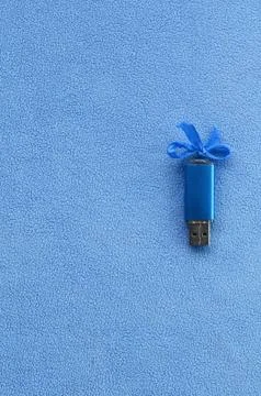 Brilliant blue usb flash memory card with a blue bow lies on a blanket of sof Stock Photos