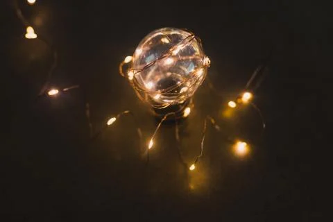 Brilliant creativity, lightbulb with string lights around it shining in the d Stock Photos