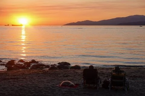 Brilliant sun dipping behind distant mountains Stock Photos