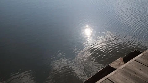 Brilliant sun glimmers on the gently undulating surface of serene water Vidéo 333903704