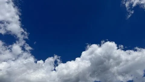 Brilliant white clouds framing a deep vibrant blue sky background Stock Photos