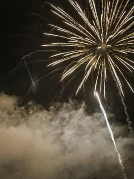 Brilliant white fireworks exploding in the dark night sky with smoke clouds.. Stock Photos