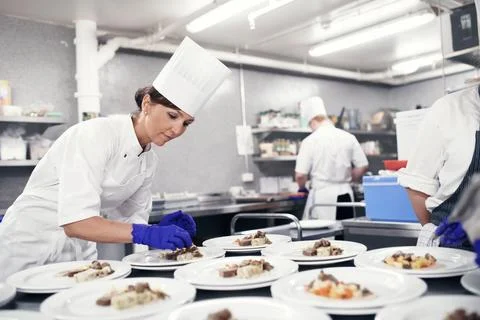 Bringing all the elements together. a chef plating food for a meal service in a Foto stock