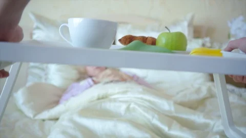 Bringing breakfast in bed while young woman is sleeping on the background Stock Footage 104461735