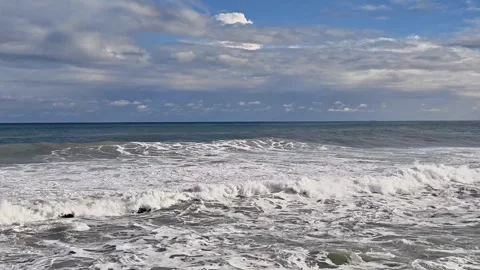 Brisk surf moves across open water. Vigorous breakers crash beneath gentle cloud Stock Footage 327780415