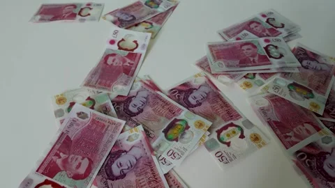 British £50 notes falling in ultra slow motion onto a white surface Stock Footage 334260977