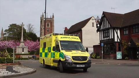 British ambulance drives passed English Church and blossom Stock Footage