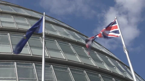 The British and EU flags waving near a glass building. Stock Footage 99946382