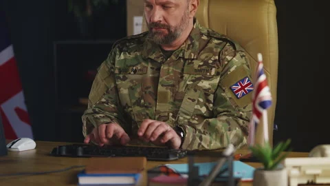 British army officer typing on computer in office, preparing military reports Stock Footage 335537297