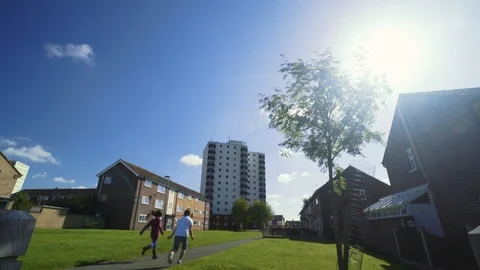 A British council estate on a sunny day with happy children running Stock Footage