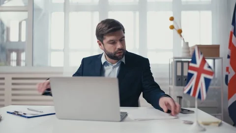 British embassy employee processing visa document, checking database on laptop Stock Footage 240835882