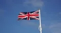 British flag waving in the wind against a clear blue sky,very windy,bird passes HD Footage