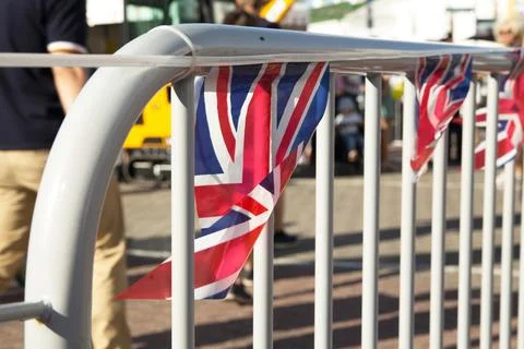 British flags are hanging from a white railing at a lively outdoor event Stock Photos