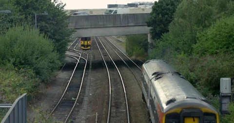 British Moving Trains under Road Bridge and Moving Traffic with Track and Trees  Stock Footage 94706062