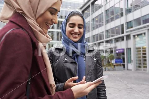British Muslim Women Texting On Mobile Phone Outside Office Stock Photos