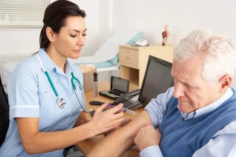 British nurse giving injection to senior man Stock Photos
