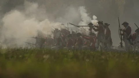 British Redcoat re-enactors on distant battlefield firing flintlock muskets Video stock 116906897