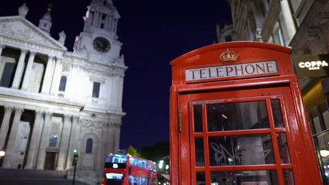 British Telephone Booth With Red Double Decker Buses in Background at Night Stock Footage 112186803