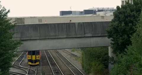 British Train with Road Bridge and Moving Traffic. Tracks and Trees in Britain Stock Footage 94706345