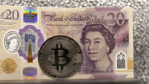 British twenty Pound note and a Bitcoin digital currency seen from several Stock Footage 321829693