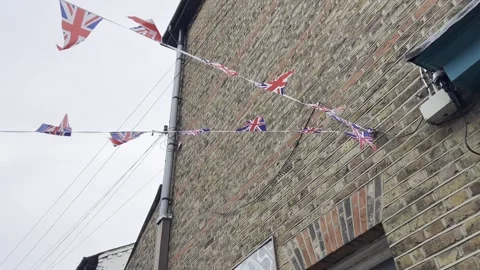 British Union Jack flags hanging at the street against brick wall Stock Footage 242585472