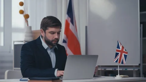 British visa officer checking citizens documents, updating database on laptop Stock Footage 240837456