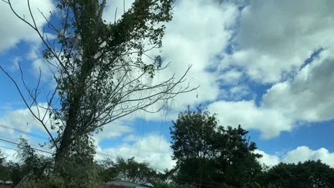 Broad cloud formations stretch overhead while blurred greenery traces the road Stock Footage 325035028