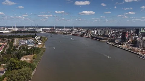 Broad Scheldt River divides Antwerp port skyline from scattered wind turbine Видео 348786182