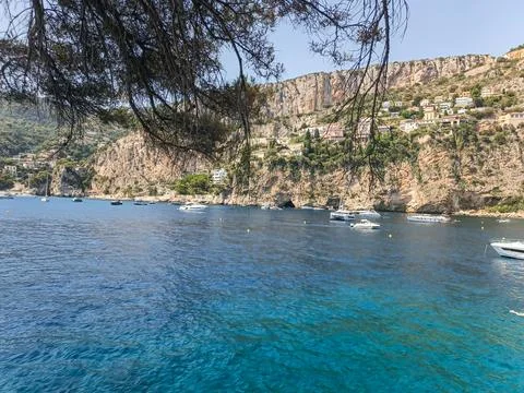 Broad view of Cap d'Ail turquoise bay under pine branch frame Photos