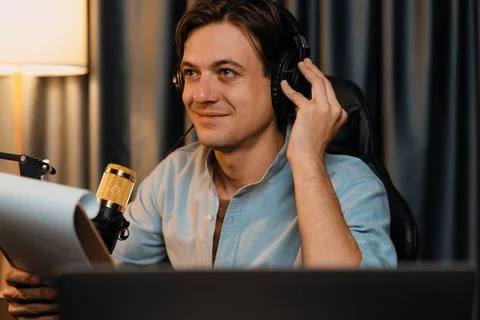 Broadcaster reading script note to listener in warm light at night. Pecuniary. Stock Photos
