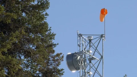 Broadcasting tower with antenna and small windsock against blue sky Stock Footage 129129776