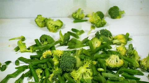 Broccoli and green beans fall onto white wooden background. Slow motion. Stock Footage 57555946