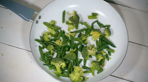 Broccoli and green beans fall into the pan. Slow motion. Stock Footage 57556493