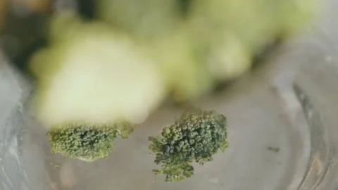 Broccoli boggles the camera and then is dropped into the water in slow Video stock 209768673