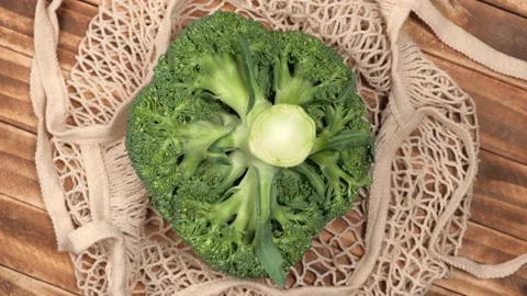 Broccoli cabbage in a string bag rotating on a wooden background. top view. 4k. Stock Footage 217671505