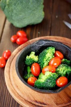 Broccoli cooked with cherry tomatoes inside a frying pan. Stock Photos