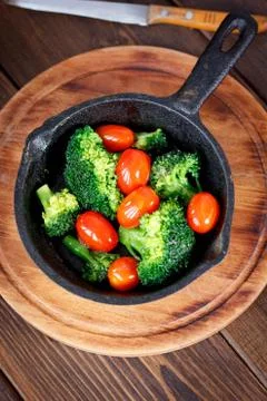 Broccoli cooked with cherry tomatoes inside a frying pan. Stock Photos