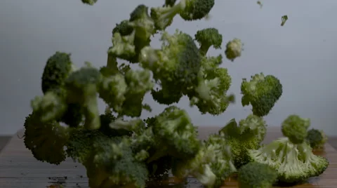 Broccoli falling in slow motion onto a cutting board Stock Footage 64256132