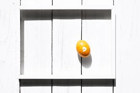 Brocken yellow easter egg in white frame on white wooden background. Happy .. Stock Photos