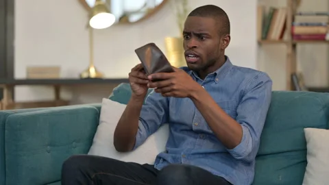 Broke Young African Man Checking Empty Wallet on Sofa Stock Footage 142737198