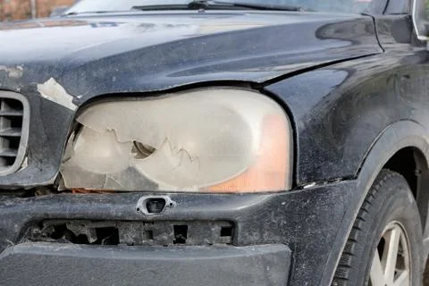 Broken by accident front headlamp on a black car, wheel background. Repairing Stock Photos