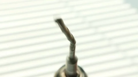 A broken and bent drill in a screwdriver is spinning on a white background. The Stock Footage 252879664