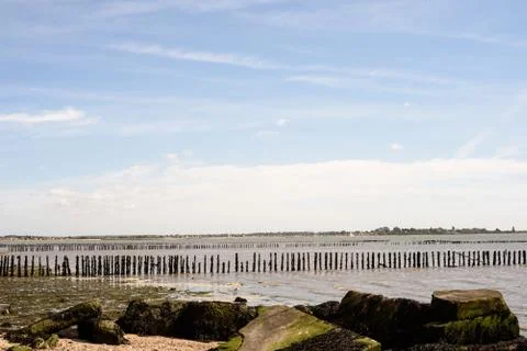 Broken and worn sea posts act as a barrier to the oncoming sea waves at Cudmo Stock Photos